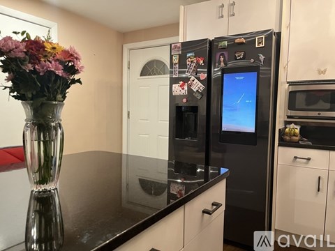 A black fridge with a screen on it in a kitchen.
