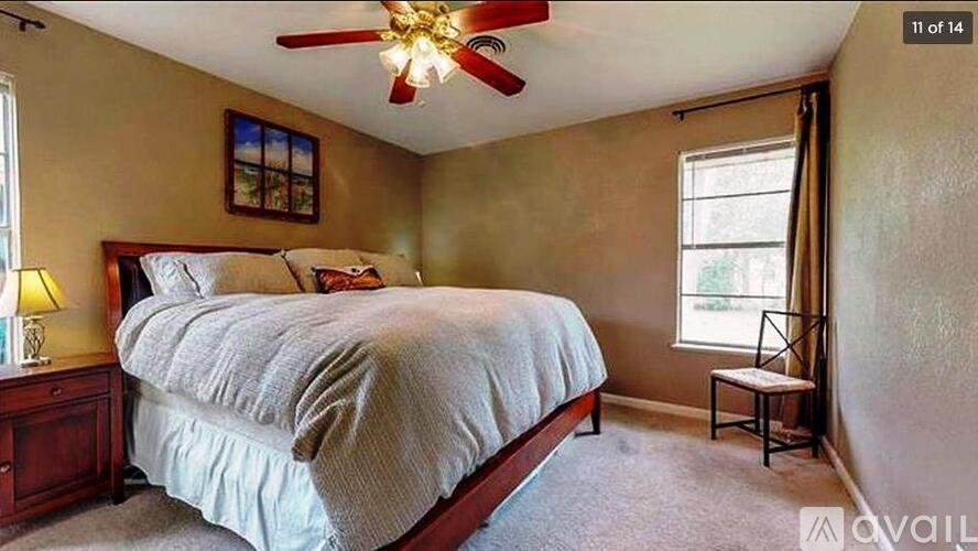 A bedroom with a bed, a ceiling fan, and a window.