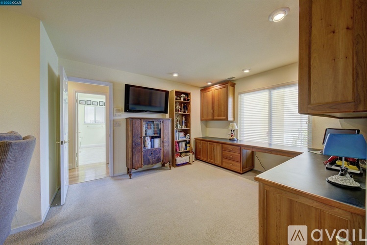 A living room with a television, bookshelf, and a desk.