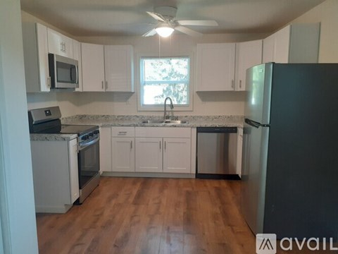 A kitchen with white cabinets and a black refrigerator.