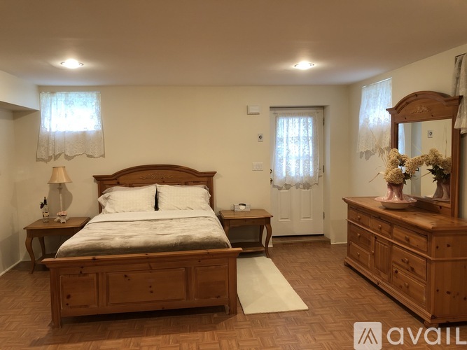 A bedroom with a large bed, wooden furniture, and a mirror.