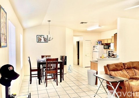 A living room with a brown couch and a dining table with chairs.