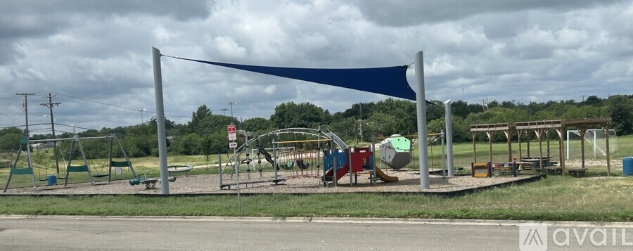 A playground with a blue canopy and a swing set.