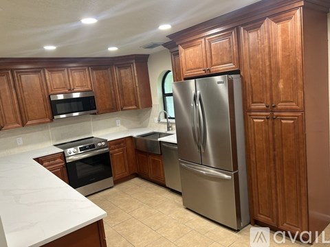 A kitchen with wooden cabinets and a stainless steel refrigerator.