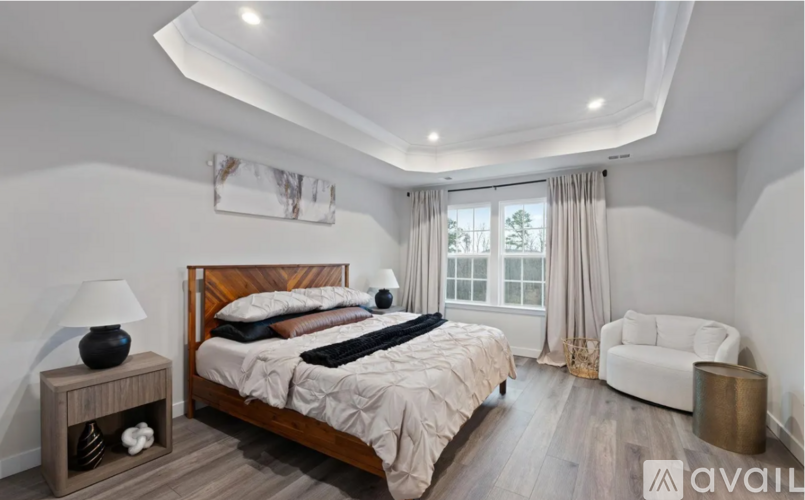 A bedroom with a large bed, a nightstand with a lamp, and a chair.