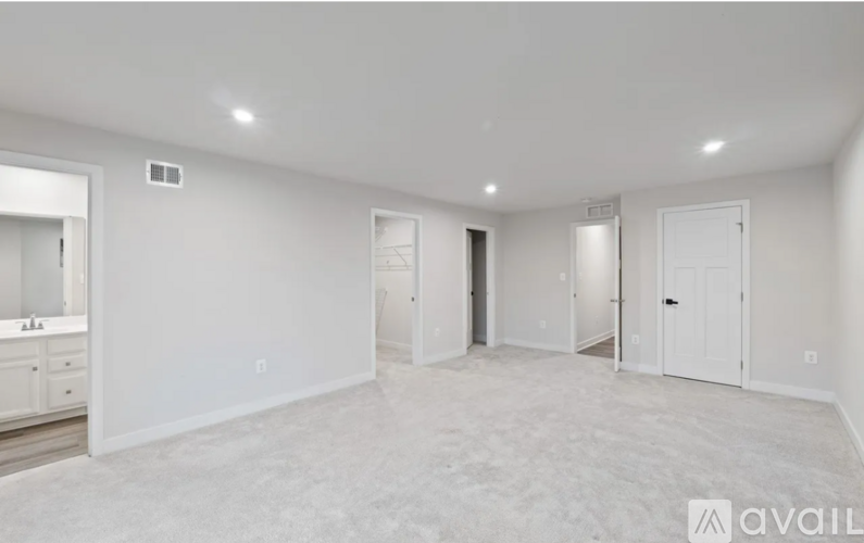 A spacious empty room with white walls and carpeted floor.