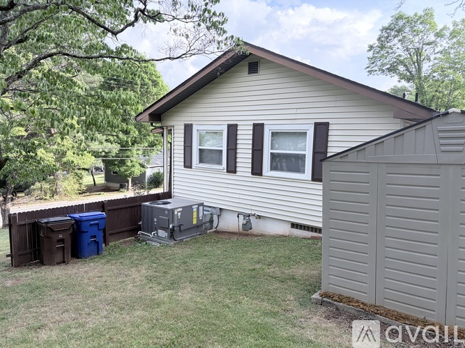 A house with a brown roof and a grey shed in the backyard.