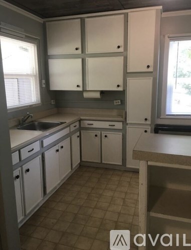 A kitchen with white cabinets and a tiled floor.