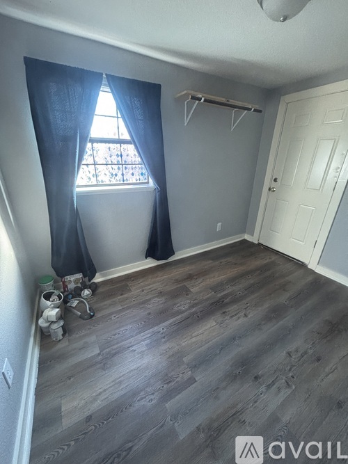 A room with a window and a wooden floor.