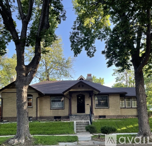 A house with a brown roof and a black front door is surrounded by trees.