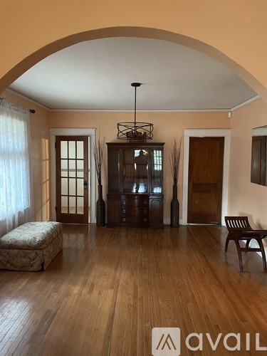 A room with wooden floors and furniture including a bench and a cabinet.