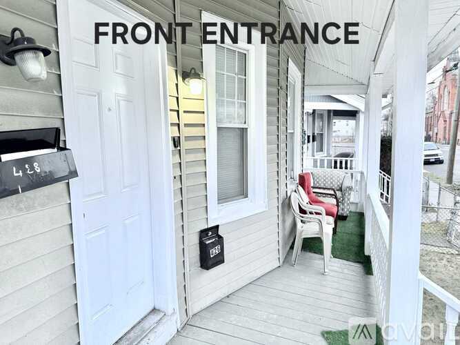 A front porch with a white door and a sign that says "Front Entrance".