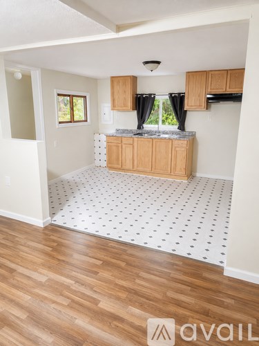 A kitchen with wooden cabinets and a white speckled floor.