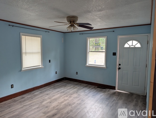 A room with blue walls, a ceiling fan, and a door.