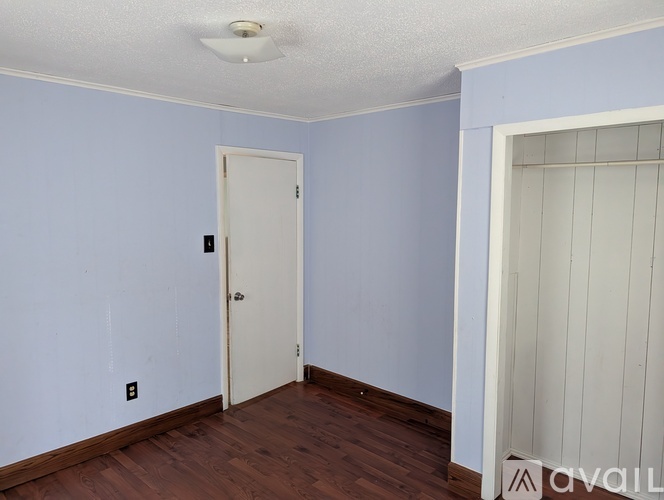 A room with a white door and a light switch on the wall.