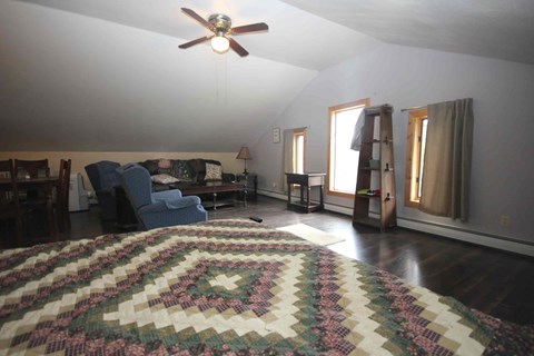 A living room with a rug on the floor and a ceiling fan above.