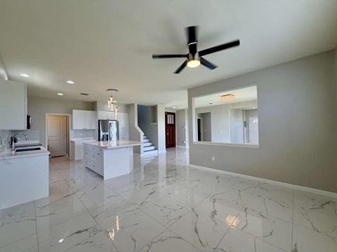 A spacious kitchen with marble flooring and a ceiling fan.