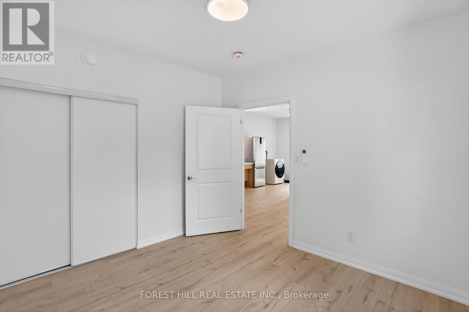 A white room with a sliding door and a brokerage sign.