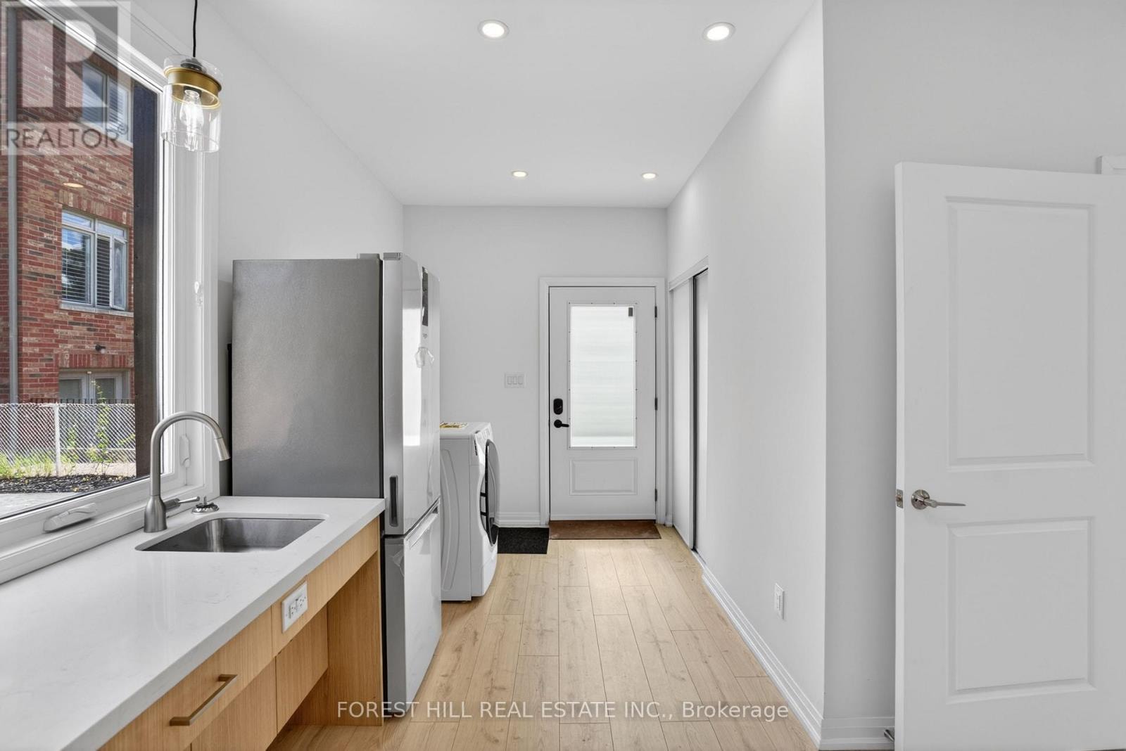 A kitchen with a sink, refrigerator, and a window.