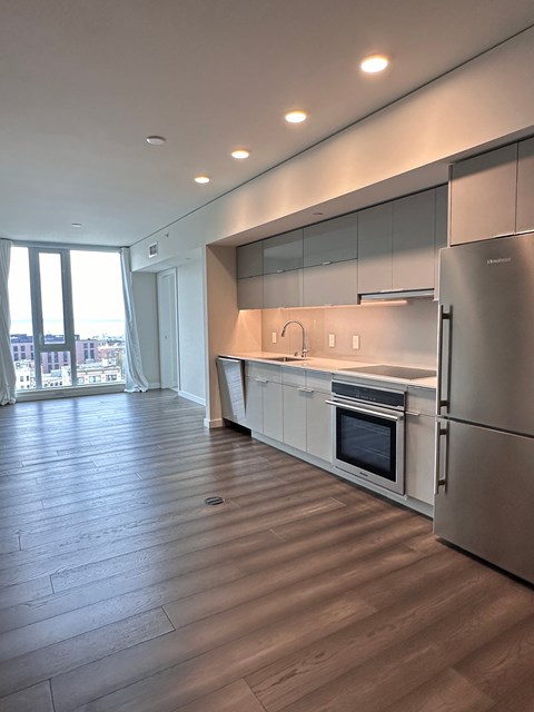 A modern kitchen with stainless steel appliances and wooden flooring.