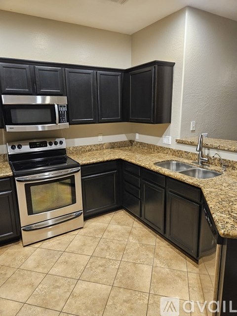 A kitchen with black cabinets and a stainless steel oven.