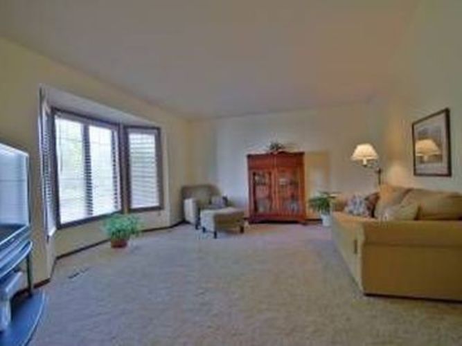 A living room with a couch, chair, and potted plant.