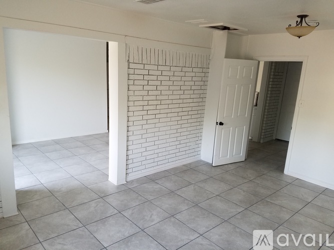A room with a white door and a brick wall.