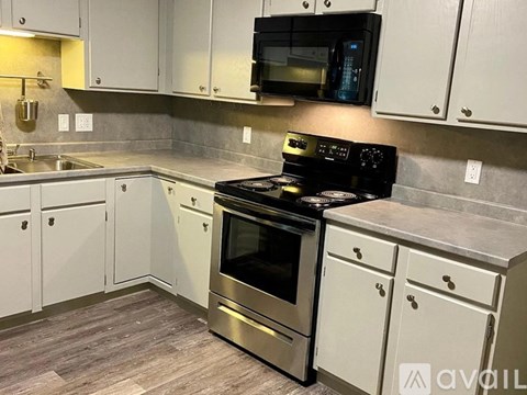 A kitchen with a black stove top oven and white cabinets.