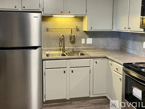 A kitchen with a stainless steel refrigerator and white cabinets.