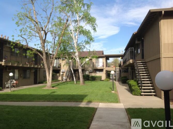 A grassy area with a walking path and apartment buildings in the background.