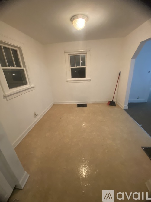 A room with a light on the ceiling and a broom leaning against the wall.