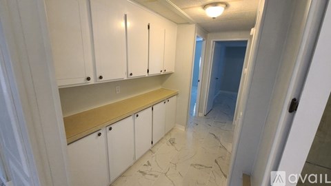 A kitchen with white cabinets and a marble floor.