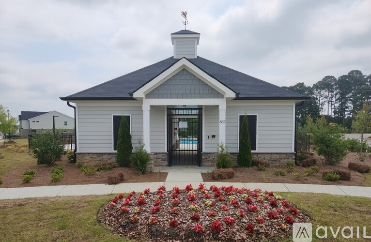A small white building with a black roof and a sign that says "AVAILABLE" in front of it.