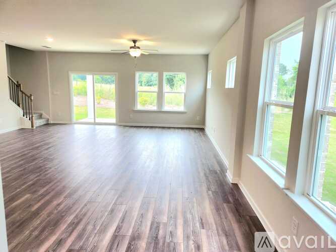 A spacious room with wooden floors and a ceiling fan.