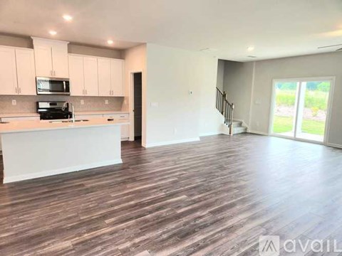 A spacious kitchen with white cabinets and a wooden floor.