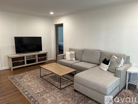 A living room with a grey couch, a wooden coffee table, and a television on a cabinet.
