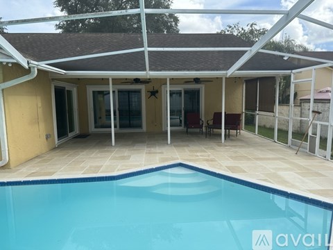 A pool in a backyard with a patio and a house.