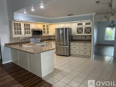 A kitchen with white cabinets and a wooden floor.