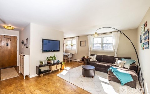 A living room with a grey couch and a television on the wall.