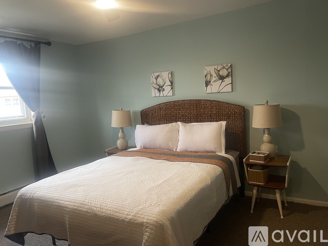 A bedroom with a large bed and two lamps.