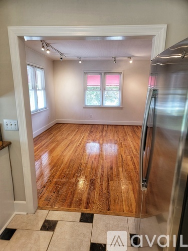 A kitchen with a wooden floor and a refrigerator.