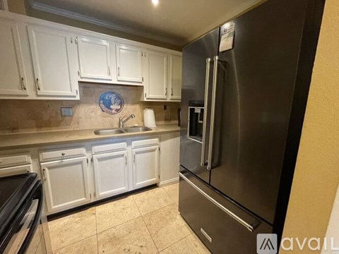 A kitchen with white cabinets and a stainless steel refrigerator.