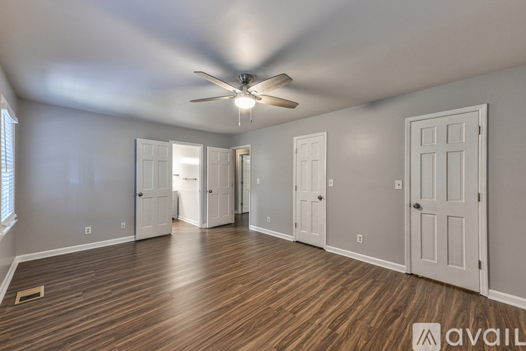 A spacious room with a ceiling fan and wooden flooring.