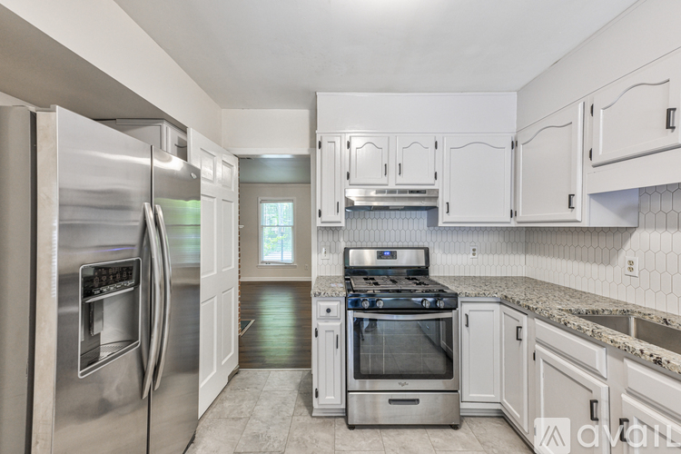 A kitchen with a stainless steel refrigerator and white cabinets.