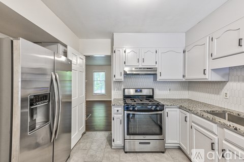 A kitchen with a stainless steel refrigerator and white cabinets.