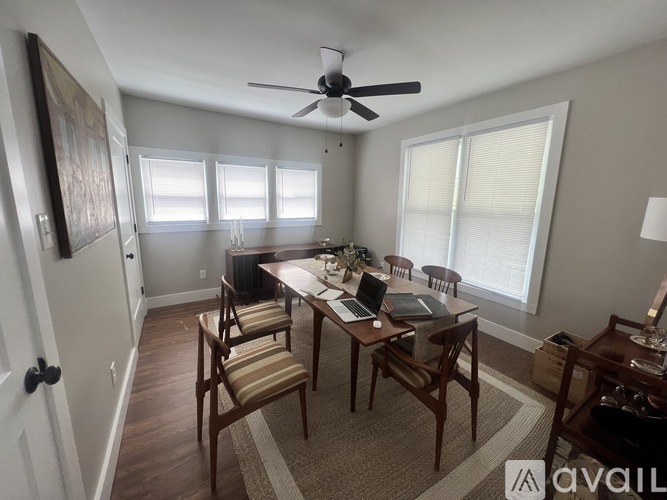 A dining room with a table set for four and a ceiling fan.
