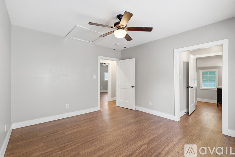 A spacious room with a ceiling fan and wooden flooring.