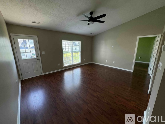 A room with a ceiling fan and wooden flooring.