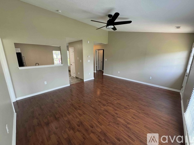 A spacious room with wooden floors and a ceiling fan.