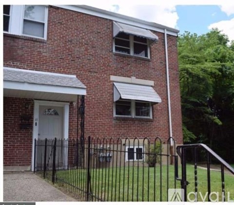 A brick house with a black fence and a white door.
